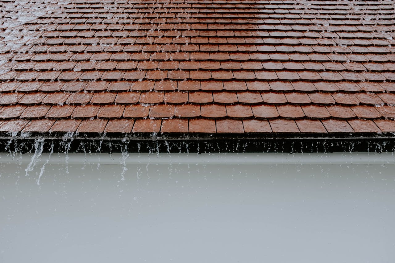 Services Brown roof tiles with rainwater cascading down, showcasing architectural texture and detail.